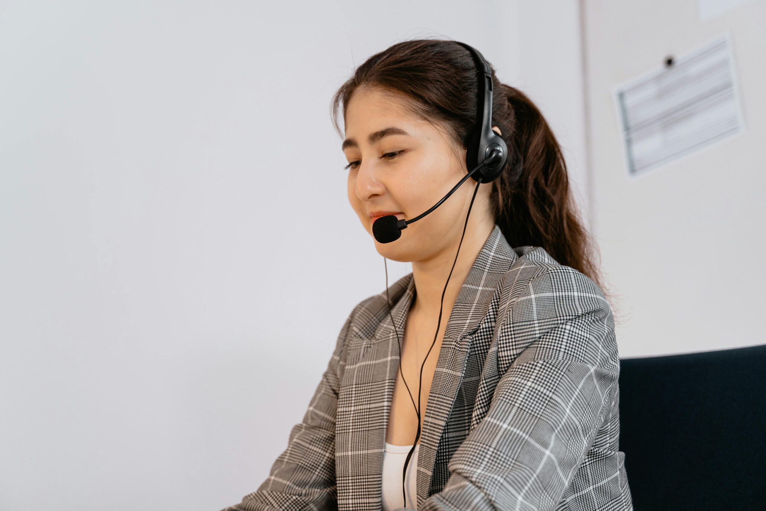 Professional woman providing customer support, wearing headset in office.